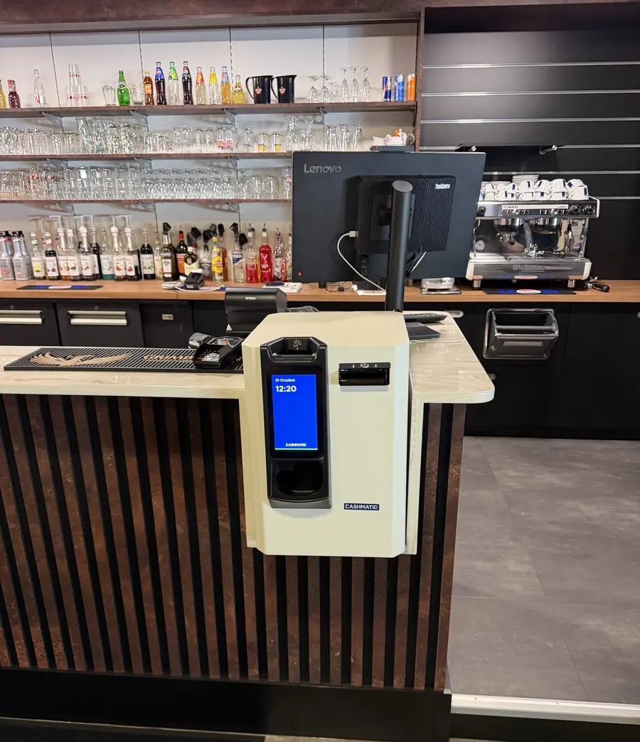 Monnayeur automatique Cashmatic fixé au comptoir d'un bar, à côté du poste de caisse