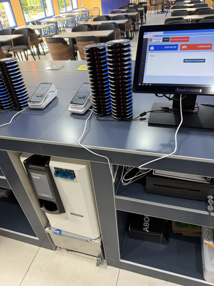 Monnayeur automatique installé sous le plan de caisse d'un self-service